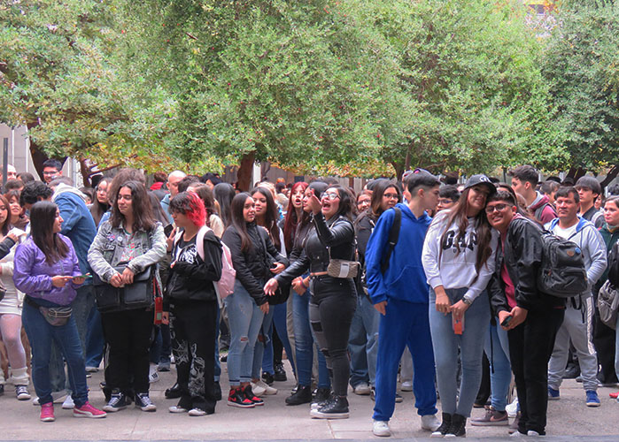 Fotografía de decenas de jóvenes de pie conversando y riendo