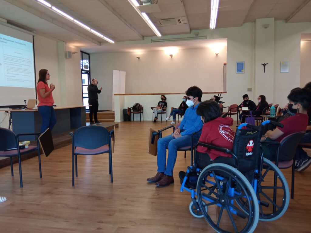 Vista del costado del auditorio, se ven algunos participantes y una de las profesionales del PIANE exponiendo.