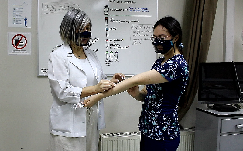 Docente y ayudante de enfermería usan mascarillas antiempañantes en clase.