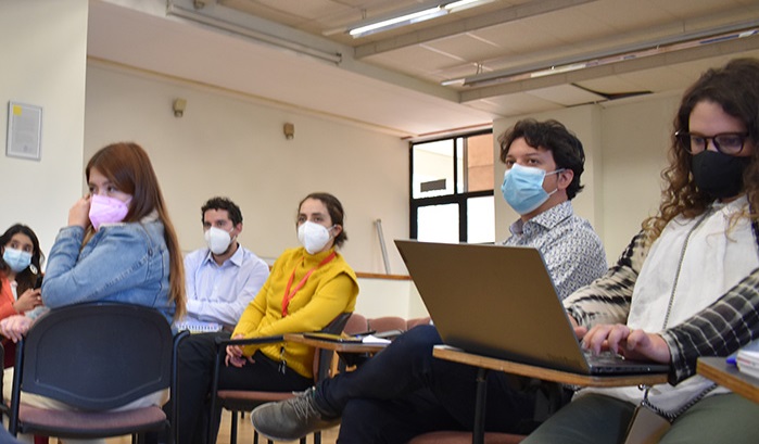 Profesionales de distintas Unidades Académicas y de la Dirección de Inclusión sentados con mascarilla en auditorio mirando hacia el frente con atención.