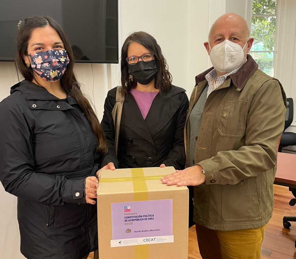 Fotografía. Profesionales de PIANE recibiendo caja con 4 tomos que componen propuesta de nueva Constitución en Braille y macrotipo.