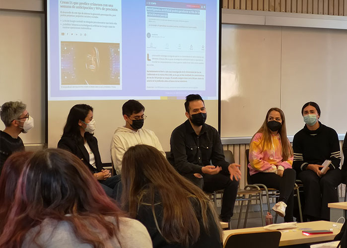Fotografía de personas con mascarilla sentadas en sillas en una fila