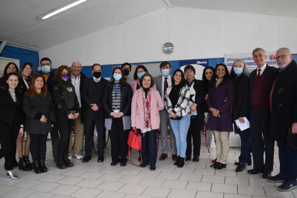 Fotografía de personas adultas, docentes y profesionales de liceos e instituciones de educación superior, posando con mascarilla para la foto junto a autoridades de la UC