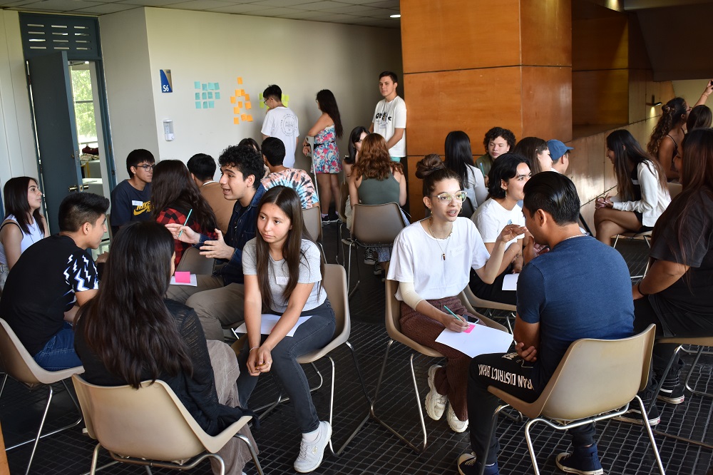 Foto de estudiantes sentados en pares frente a frente