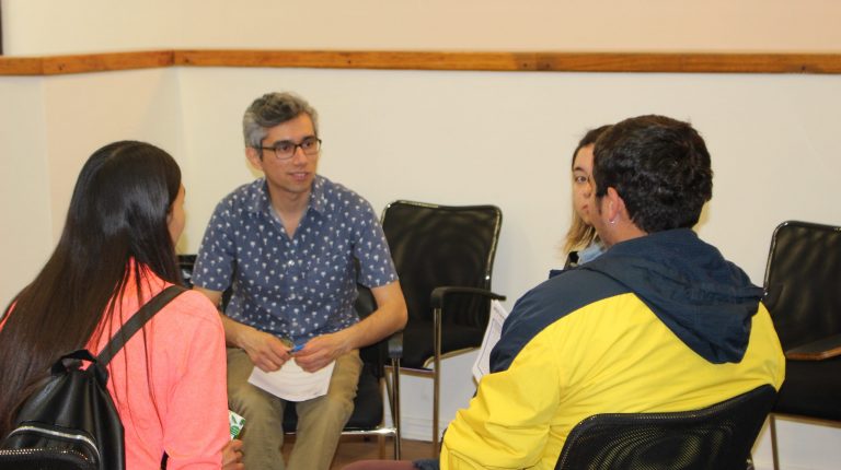 Tutor profesional del programa PACE UC sentado guiando a tres estudiantes UC, dispuestos en forma circular.