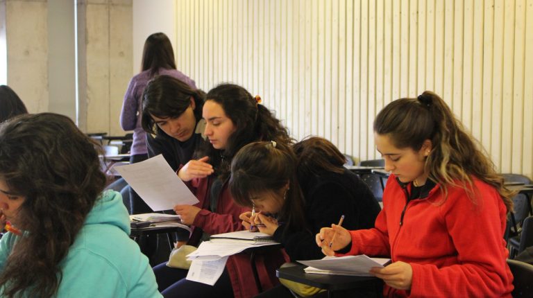Se encuentran estudiantes realizando ejercicios en clase e interactuando con ayudantes.