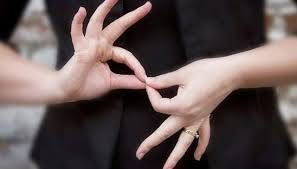 Dos estudiantes sordas sentadas en el pasto fuera de la Facultad de Educación en Campus San Joaquín conversando mediante Lengua de Señas Chilena.