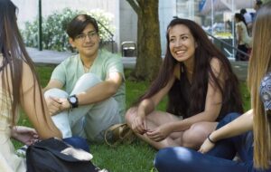 Estudiantes sentados en el pasto sonriendo.