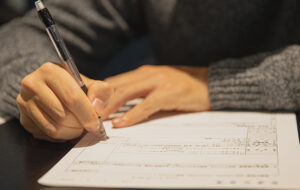 Joven escribiendo, no se ve su rostro.