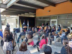 Panorámica del evento. Se ven asistentes al evento, sentados, de espalda. De frente, Vicerrector hablando en podio.