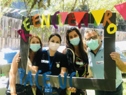 Profesionales de la Dirección de Inclusión, estudiantes y profesionales de liceos PACE UC posando con mascarilla tomando un marco de fotos gigante de papel con las palabras "Reencuentro PACE UC".