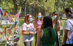 Estudiante de años superiores de pie junto a estudiantes novatas, frente a columnas de papeles post-it con deseos sobre diversidad e inclusión para la comunidad UC