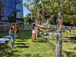 Estudiantes frente a hileras de banderines de colores colgando.