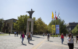 Personas entrando al Campus San Joaquín, se ve estatua de Cristo en la entrada.