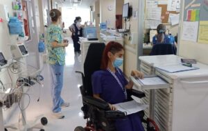 Estudiante en silla de ruedas, con su traje de nutricionista, saca elmentos de una estación de trabajo