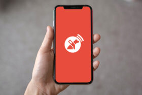 Fotografía de una mano sosteniendo celular con el logo de la aplicación de orientación para personas ciegas Lazarillo.