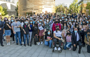 Fotografía de decenas de jóvenes y algunas personas adultas agrupadas posando para la foto con las manos levantadas