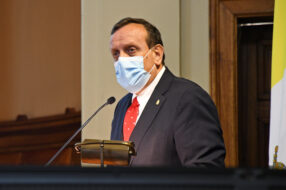 Fotografía del Rector UC Ignacio Sánchez con mascarilla frente a un micrófono mirando hacia la izquierda