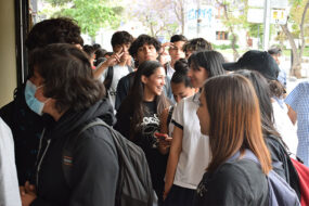Escolares de pie, mirándose entre sí, sonriendo.