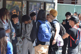 Fotografía de Jóvenes fuera de un edificio con posters enmarcados en la pared.
