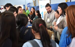Profesionales de PACE UC entregando información a estudiantes secundarios en stand de Feria Vocacional