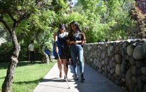Profesionales UC realizando ejercicio práctico sobre cómo asistir a persona con discapacidad visual por el Campus San Joaquín