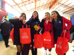 Estudiantes de Liceo Técnico San Miguel posando con merchandising de instituciones que participan en Feria Vocacional