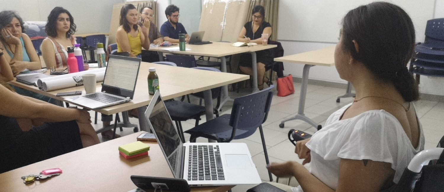 En la foto, Andrea Vásquez, coordinadora de PIANE UC expone frente a 6 profesores de Letras UC sobre adecuaciones y acompañamiento para estudiantes con Necesidades Educativas Especiales.