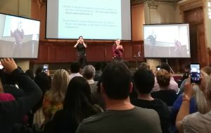 Paddy Ladd, parado en escenario junto a su intérprete oyente de Lengua de Señas de Inglaterra, en el contexto del seminario “Construyendo puentes para la educación de personas sordas”.